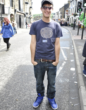 Street style contestant in jeans and a t-shirt, wearing a cap and shades